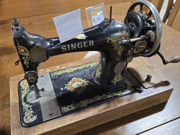 Antieke Singer naaimachine met zwart gietijzer en decoratief ingelegd motief op houten voet