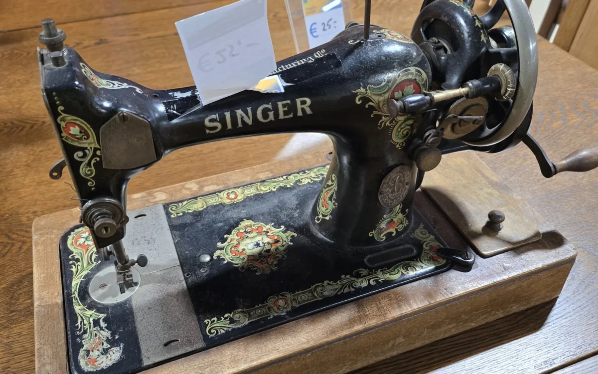 Antieke Singer naaimachine met zwart gietijzer en decoratief ingelegd motief op houten voet