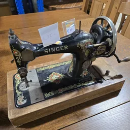Antieke Singer naaimachine met zwart gietijzer en decoratief ingelegd motief op houten voet