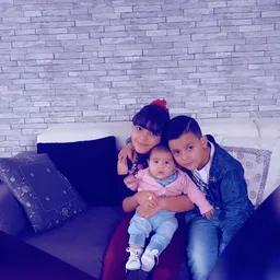 Drie kinderen zittend op een bank tegen een bakstenen muur
