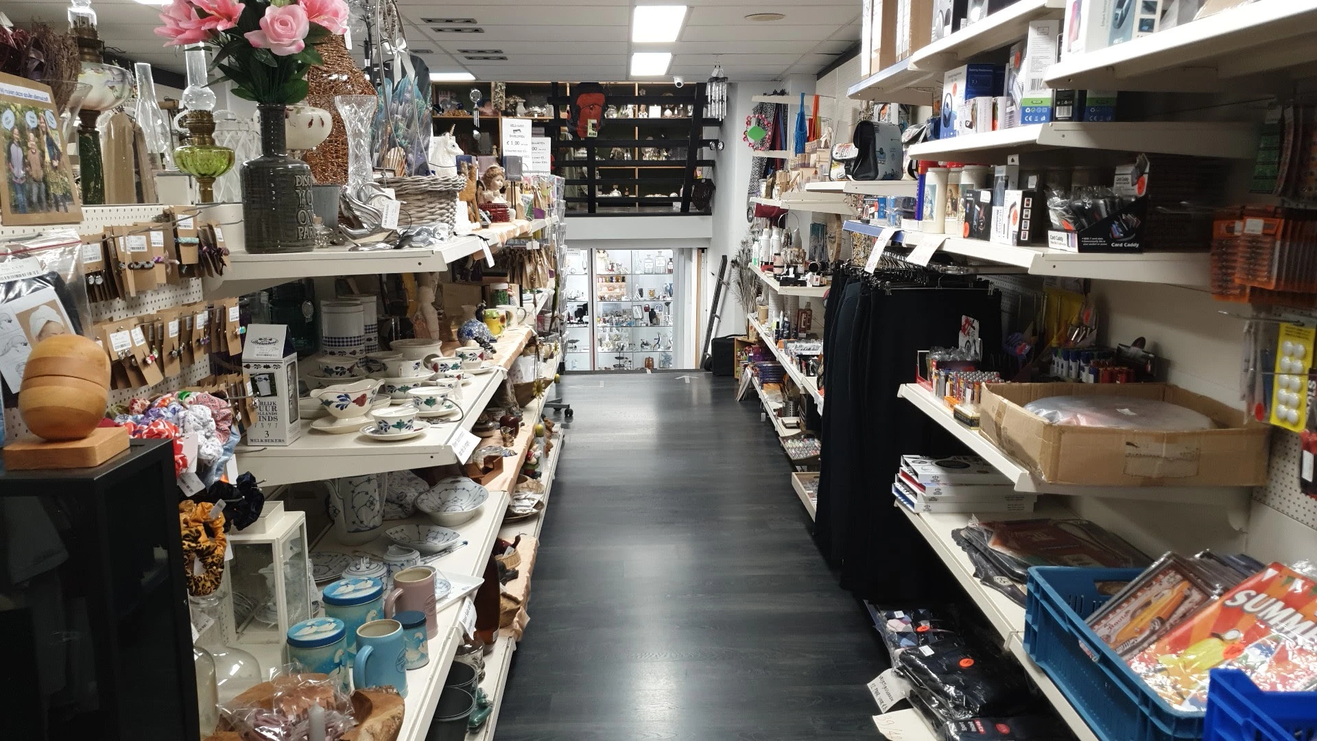 Winkelinterieur met schappen vol huishoudelijke artikelen, decoraties en diversen.