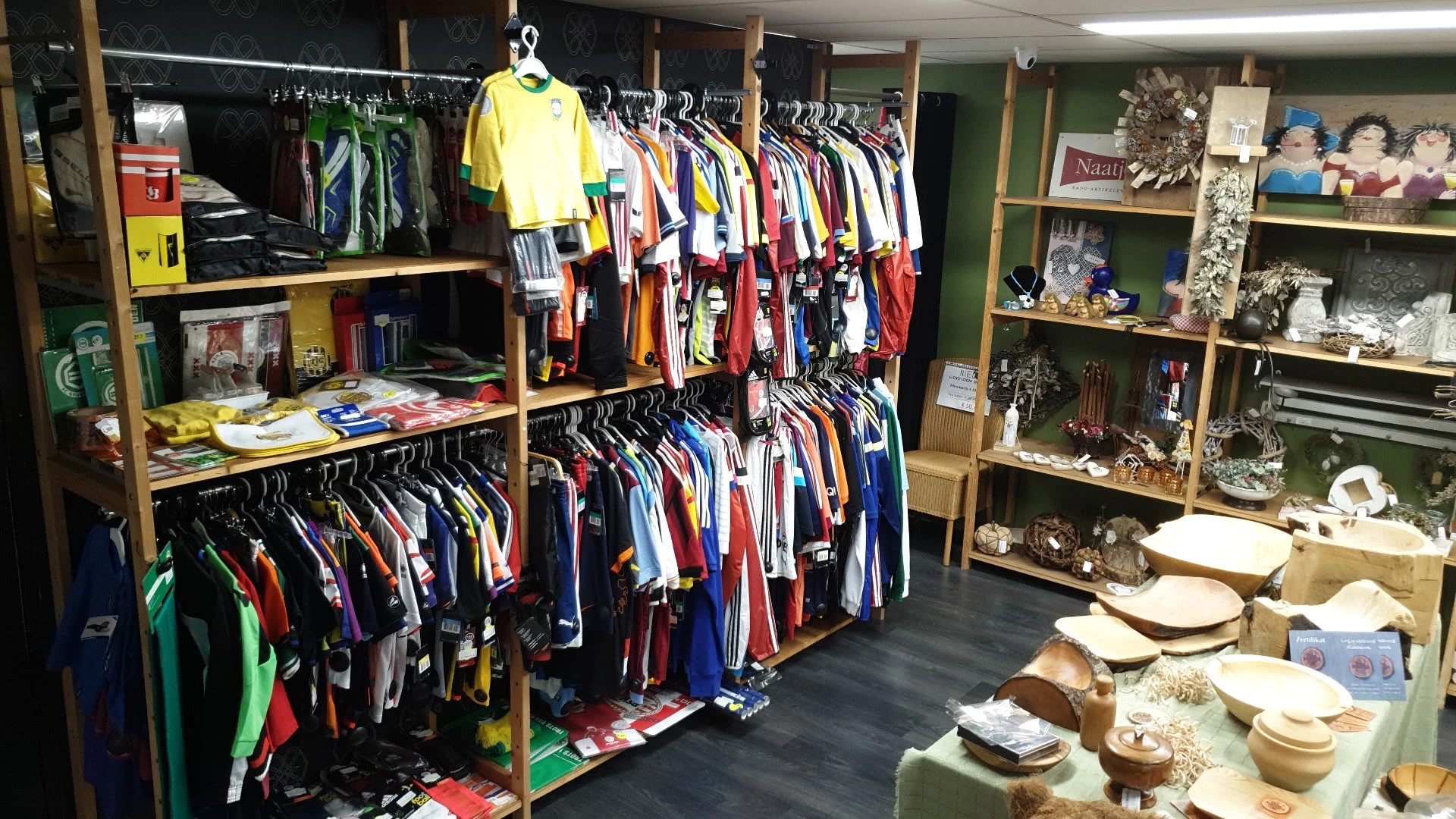Winkelinterieur met kledingrekken vol tweedehands kleding en houten stellingen met decoratie-artikelen