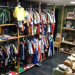 Winkelinterieur met kledingrekken vol tweedehands kleding en houten stellingen met decoratie-artikelen