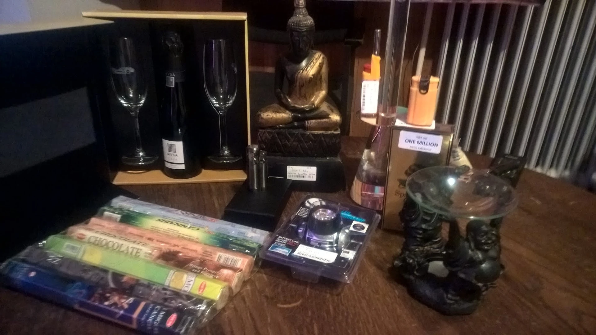 Vitrinekast met decoratieve artikelen: wijnflessen, glazen, gouden beeldje, boeken en zwarte sculpturen