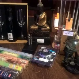 Vitrinekast met decoratieve artikelen: wijnflessen, glazen, gouden beeldje, boeken en zwarte sculpturen