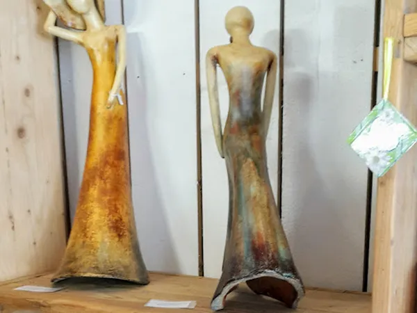 Twee gouden beeldhouwwerken van abstracte vrouwenfiguren op een houten plank