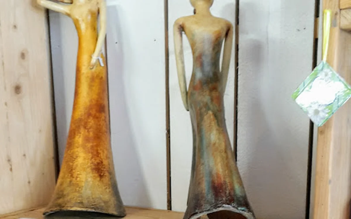 Twee gouden beeldhouwwerken van abstracte vrouwenfiguren op een houten plank