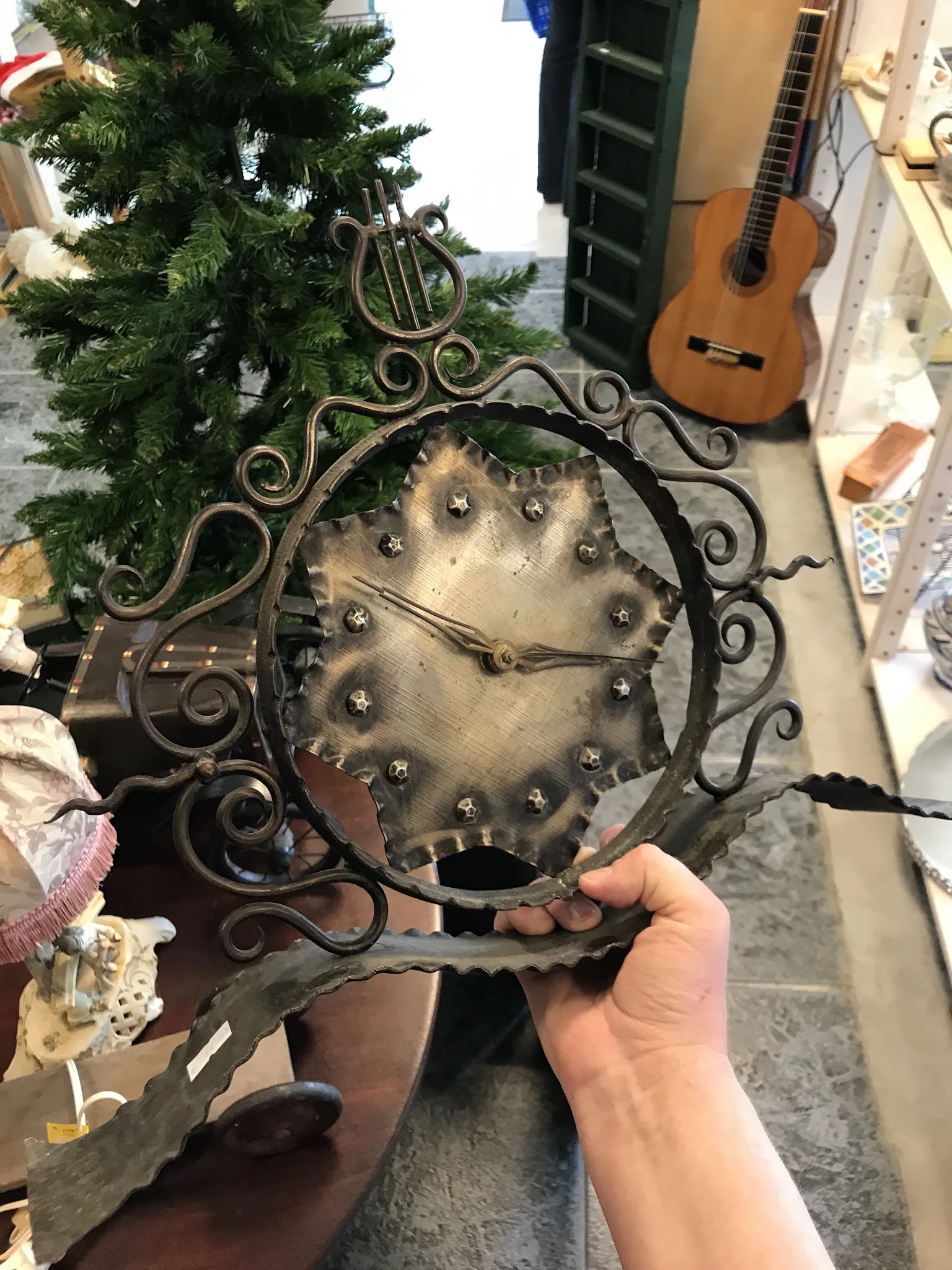 Decoratieve metalen wandschaal met gestuikt patroon in ornamentale lijst, gehouden in de hand