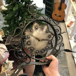 Decoratieve metalen wandschaal met gestuikt patroon in ornamentale lijst, gehouden in de hand