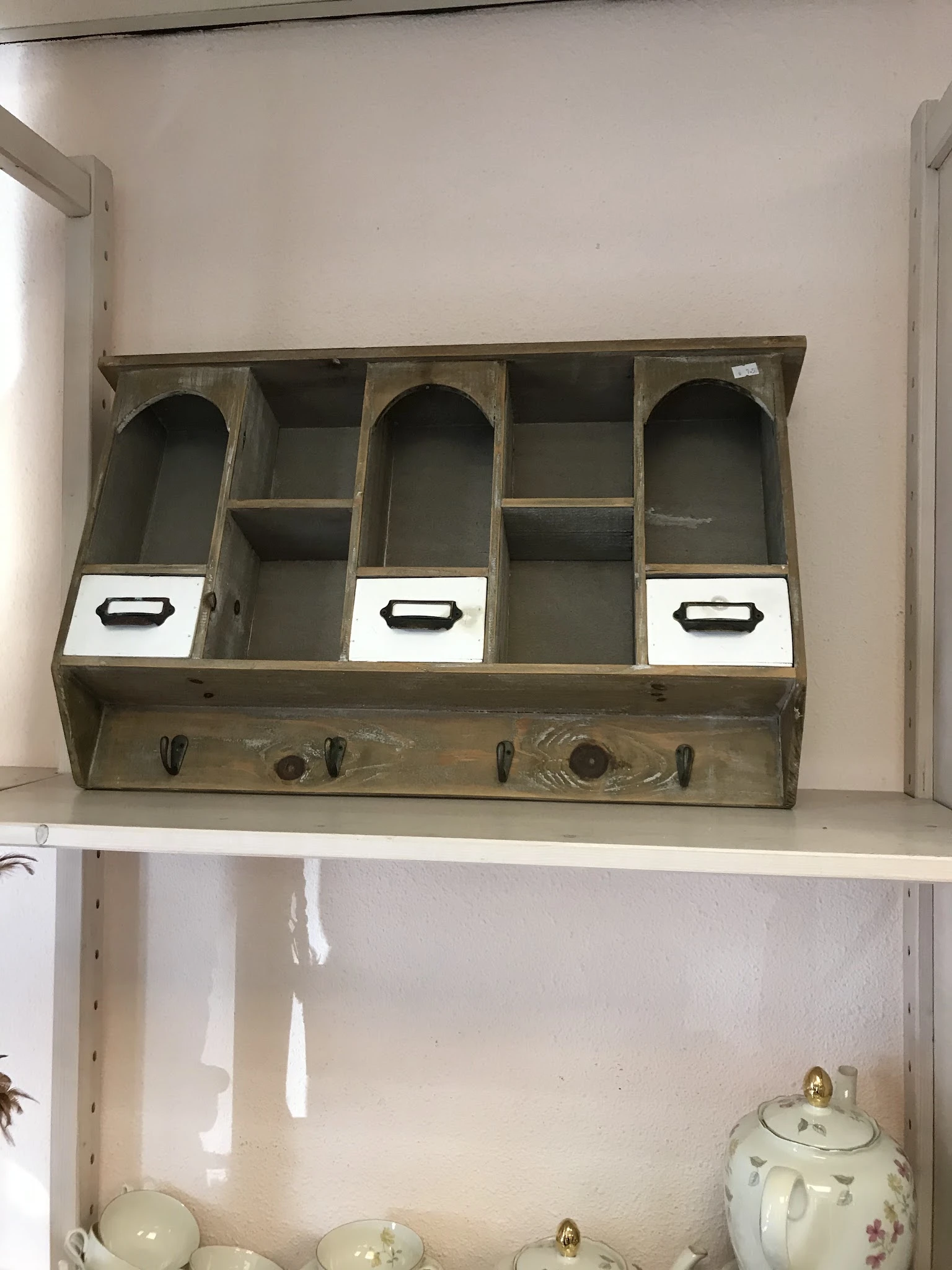 Vintage houten organizer met vijf vakken, drie daarvan met witte laden en zwarte handgrepen, onderaan vier haken