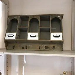 Vintage houten organizer met vijf vakken, drie daarvan met witte laden en zwarte handgrepen, onderaan vier haken