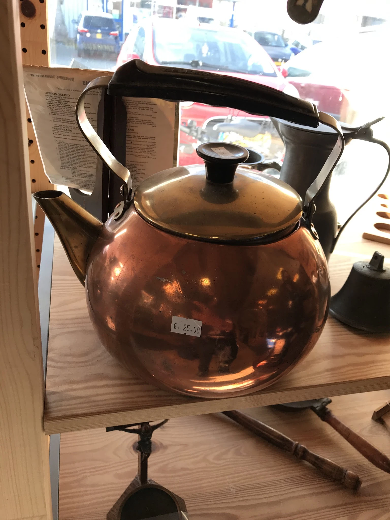 Glanzende koperen theepot met zwart deksel en handvat op houten tafel