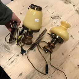 Drie vintage tafellampjes met gele glazen kappen en houten voeten op houten vloer
