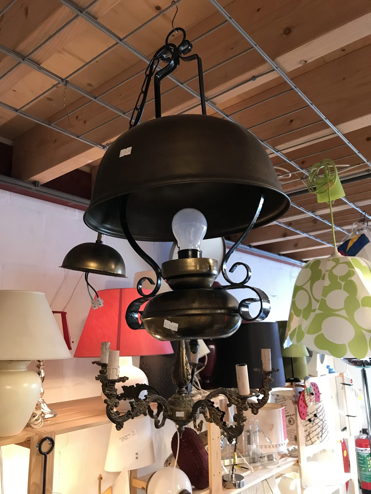 Zwarte hanglamp met koperen accenten en gebogen armen, tentoongesteld in een kringloopwinkel
