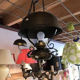 Zwarte hanglamp met koperen accenten en gebogen armen, tentoongesteld in een kringloopwinkel
