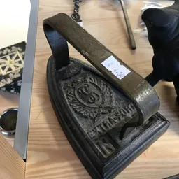 Close-up van een antieke gietijzeren steenklopper met ornamentaal motief en handvat
