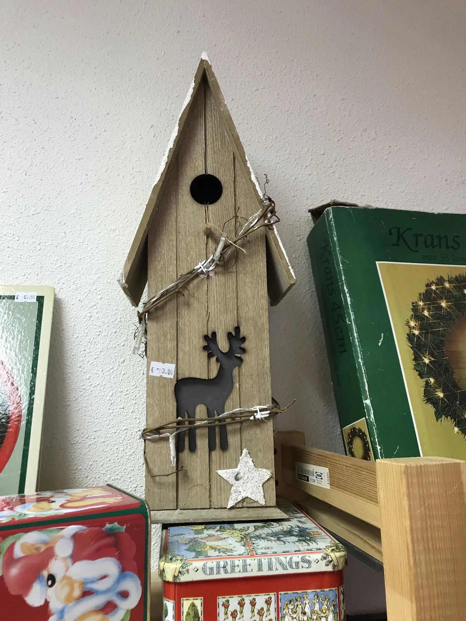 Houten vogelhuisje met zwarte silhouet van een hert en decoratieve takken eraan opgehangen