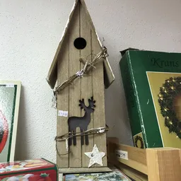 Houten vogelhuisje met zwarte silhouet van een hert en decoratieve takken eraan opgehangen