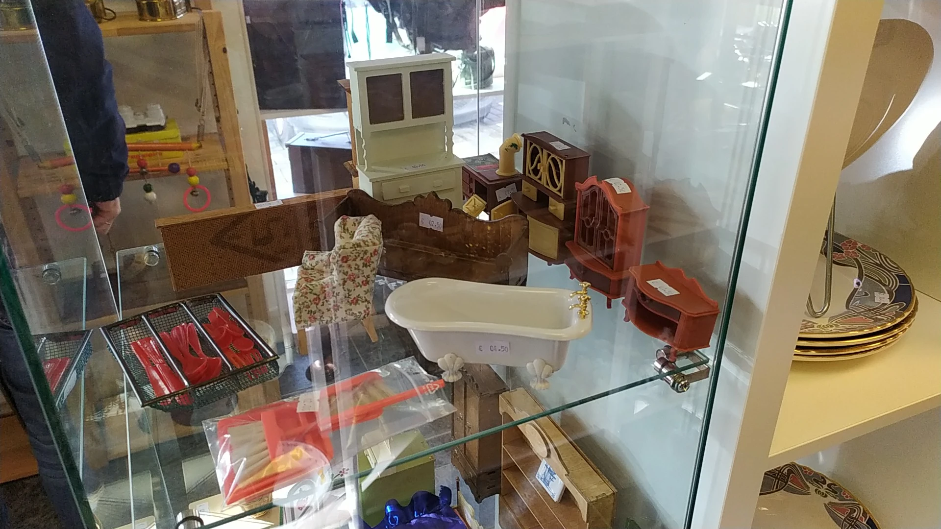 Vitrinekast met vintage huishoudartikelen en meubeltjes, waaronder een oude computer, popcornmachine, serviesgoed en houten s