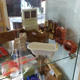 Vitrinekast met vintage huishoudartikelen en meubeltjes, waaronder een oude computer, popcornmachine, serviesgoed en houten s