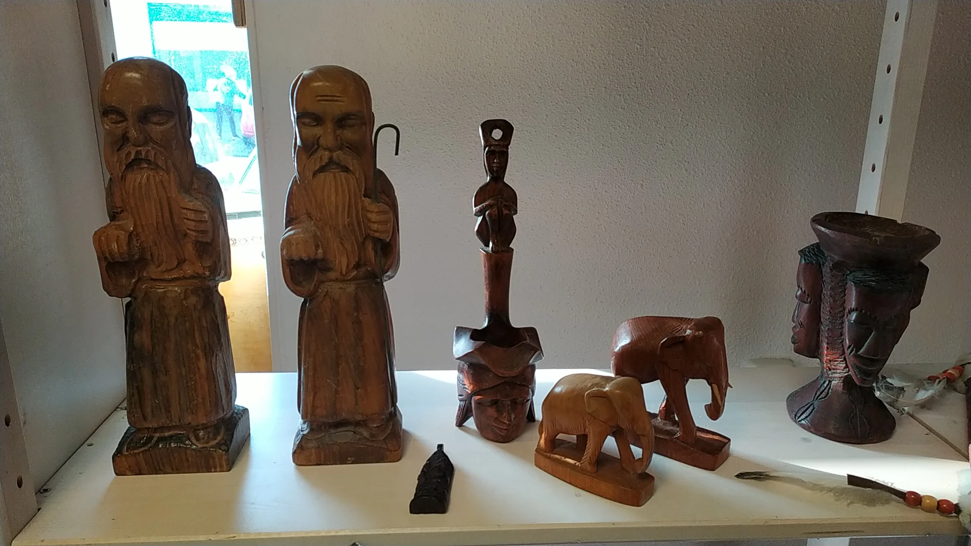 Uitgestalde houten beeldjes en sculpturen op een display: houten figuren, olifanten en decoratieve objecten