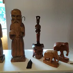 Uitgestalde houten beeldjes en sculpturen op een display: houten figuren, olifanten en decoratieve objecten