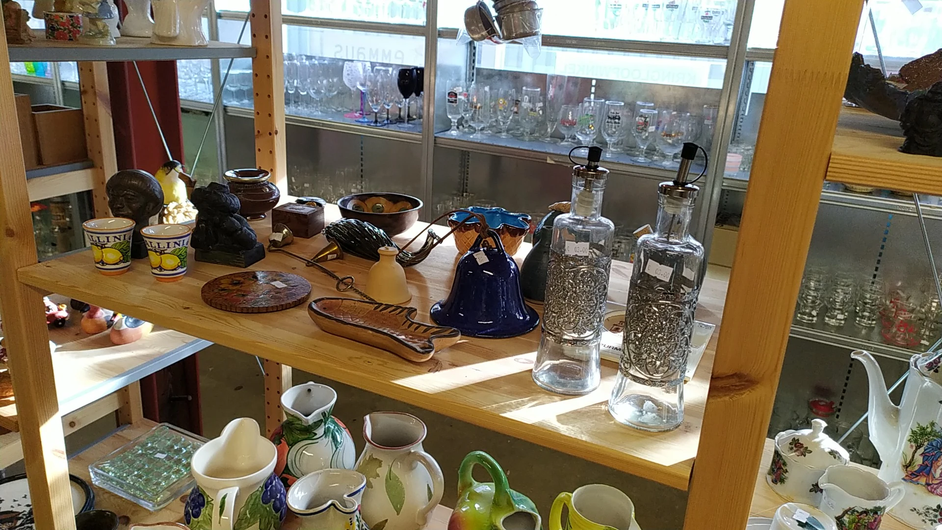 Tweedehands huishoudartikelen en servies op houten tafel onder raam met stadszicht