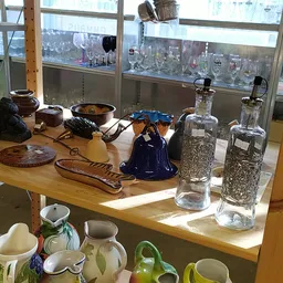 Tweedehands huishoudartikelen en servies op houten tafel onder raam met stadszicht