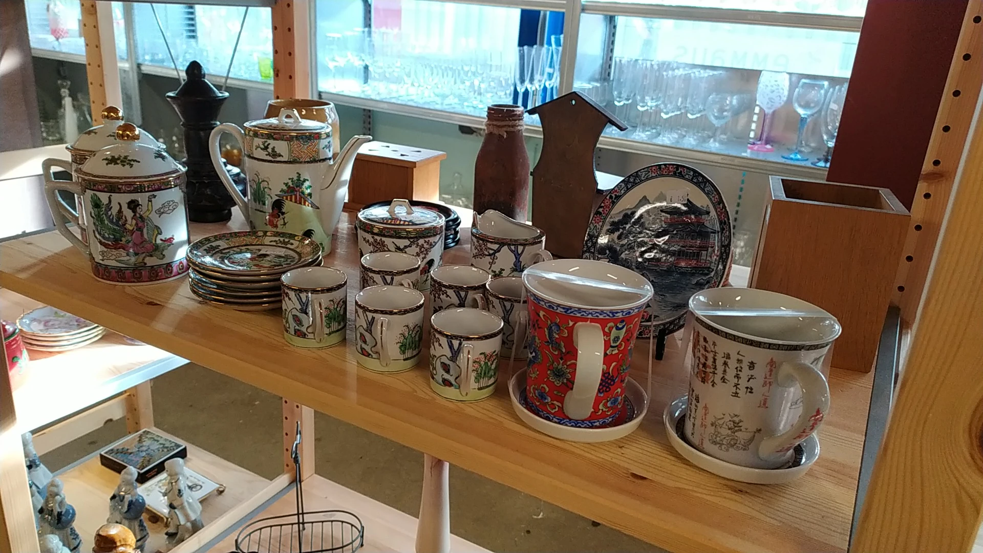 Uitgestalde verzameling vintage servies, porseleinen bekers en decoratieve items op houten tafel