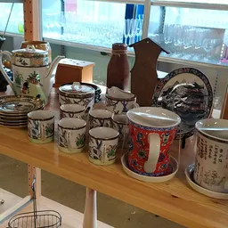 Uitgestalde verzameling vintage servies, porseleinen bekers en decoratieve items op houten tafel