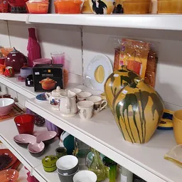 Schappen met uitgestalde serviesgoed, glazen, kannen en huishoudartikelen in verschillende kleuren