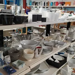Tafel vol serviesgoed, schalen, borden en huishoudartikelen in een kringloopwinkel