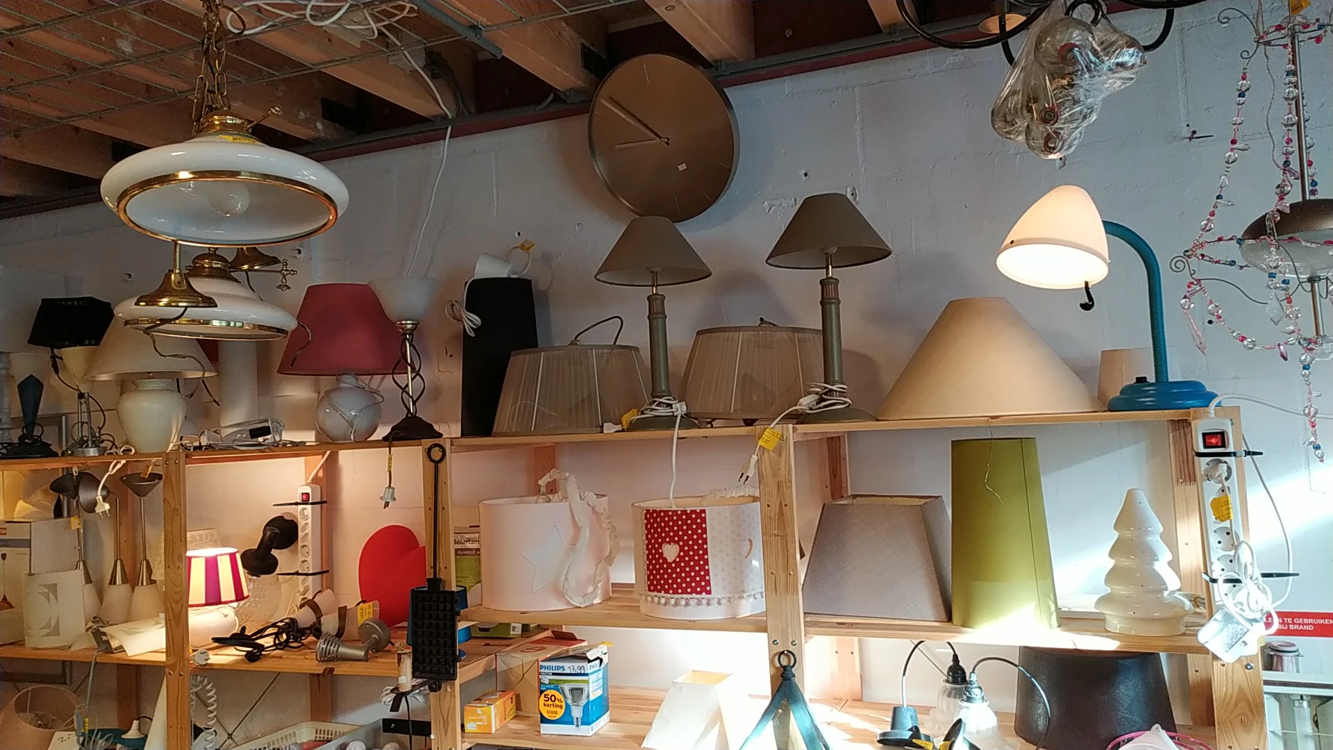 Uitgestalde lampen en lampenkappen op houten stellingen in verschillende kleuren en stijlen