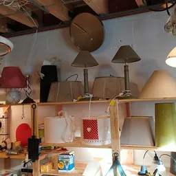 Uitgestalde lampen en lampenkappen op houten stellingen in verschillende kleuren en stijlen