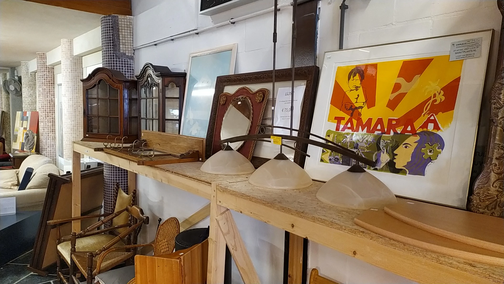 Verschillende meubels en huishoudartikelen op een houten tafel en in vitrines, waaronder lampen, spiegels en decoratieve item