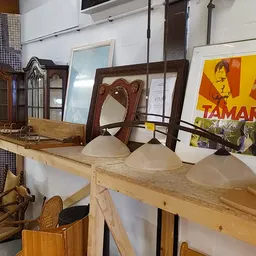 Verschillende meubels en huishoudartikelen op een houten tafel en in vitrines, waaronder lampen, spiegels en decoratieve item