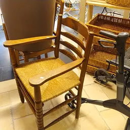 Houten stoel met rieten zitting en bruine rugleuning, geëxposeerd in de winkel