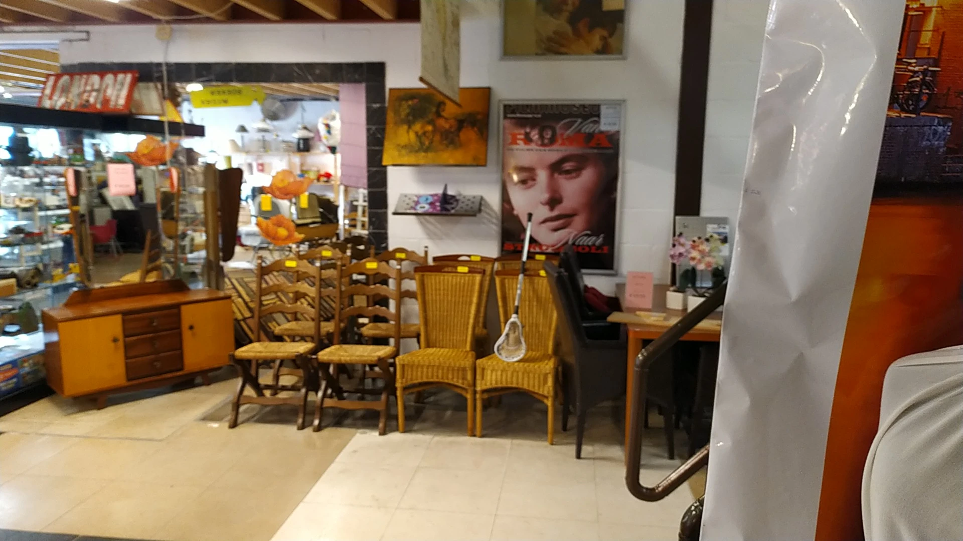 Winkelinterieur met uitgestalde meubels, stoelen en decoratie tegen muren met posters en afbeeldingen