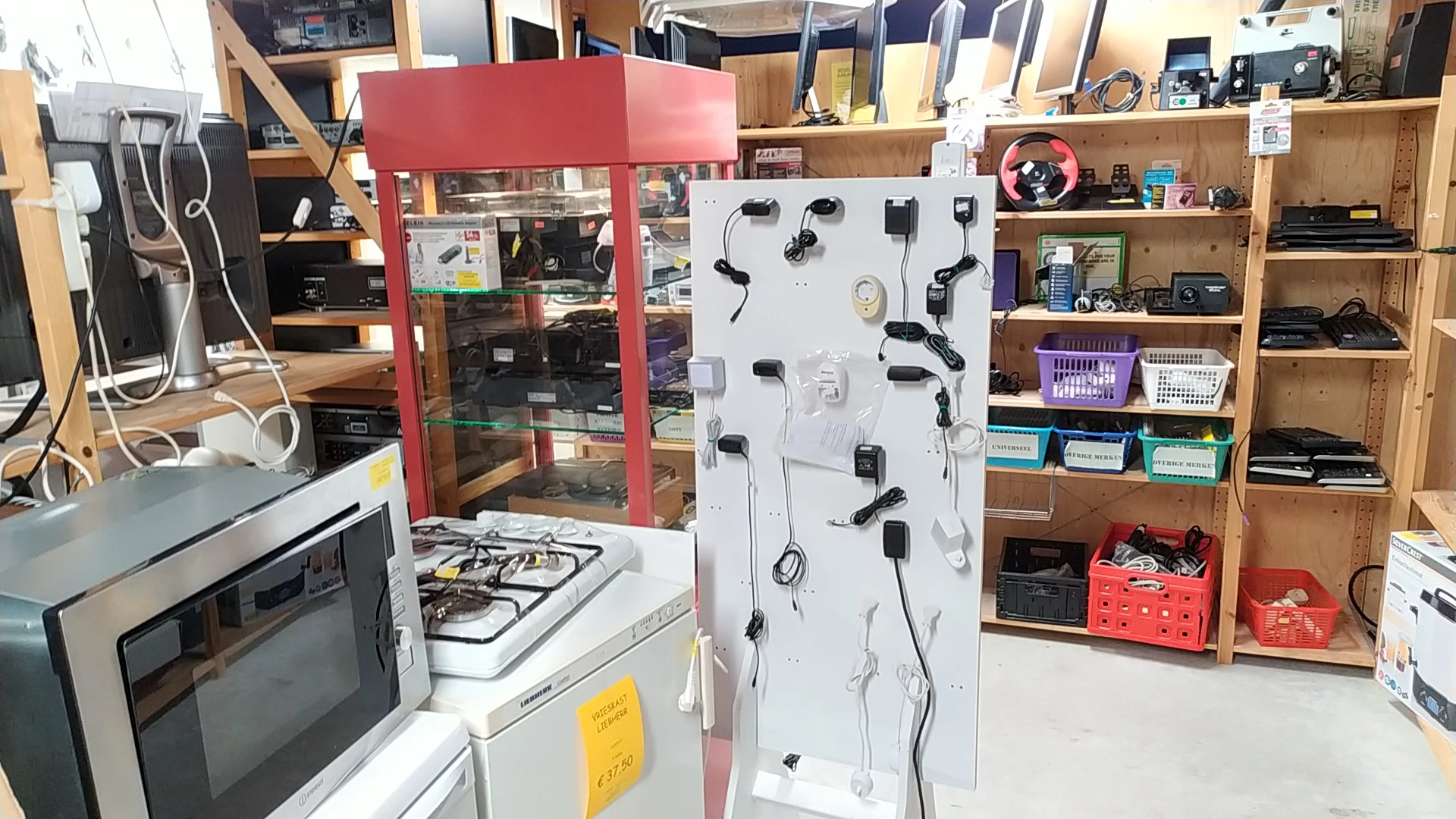 Witte display met uitgestalde zwarte oordopjes en koptelefoons in een kringloopwinkel