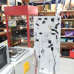 Witte display met uitgestalde zwarte oordopjes en koptelefoons in een kringloopwinkel