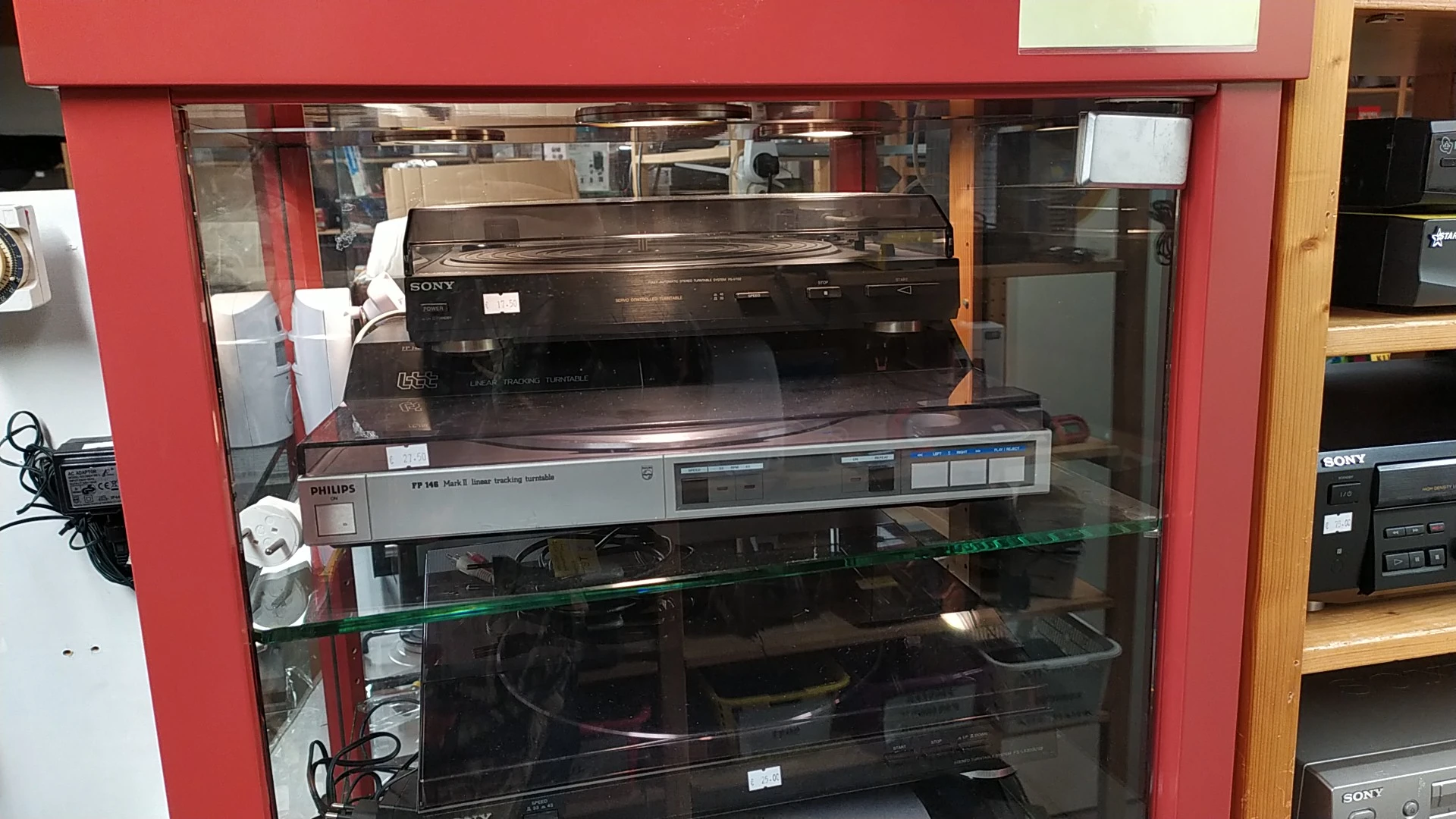Vitrinekast met vintage electronica apparaten zoals videospelers en andere elektronische apparatuur