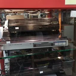 Vitrinekast met vintage electronica apparaten zoals videospelers en andere elektronische apparatuur