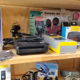 Stellingkast met elektronische apparaten en accessoires zoals karaoke-sets, speakers, apparatuur en verpakte goederen