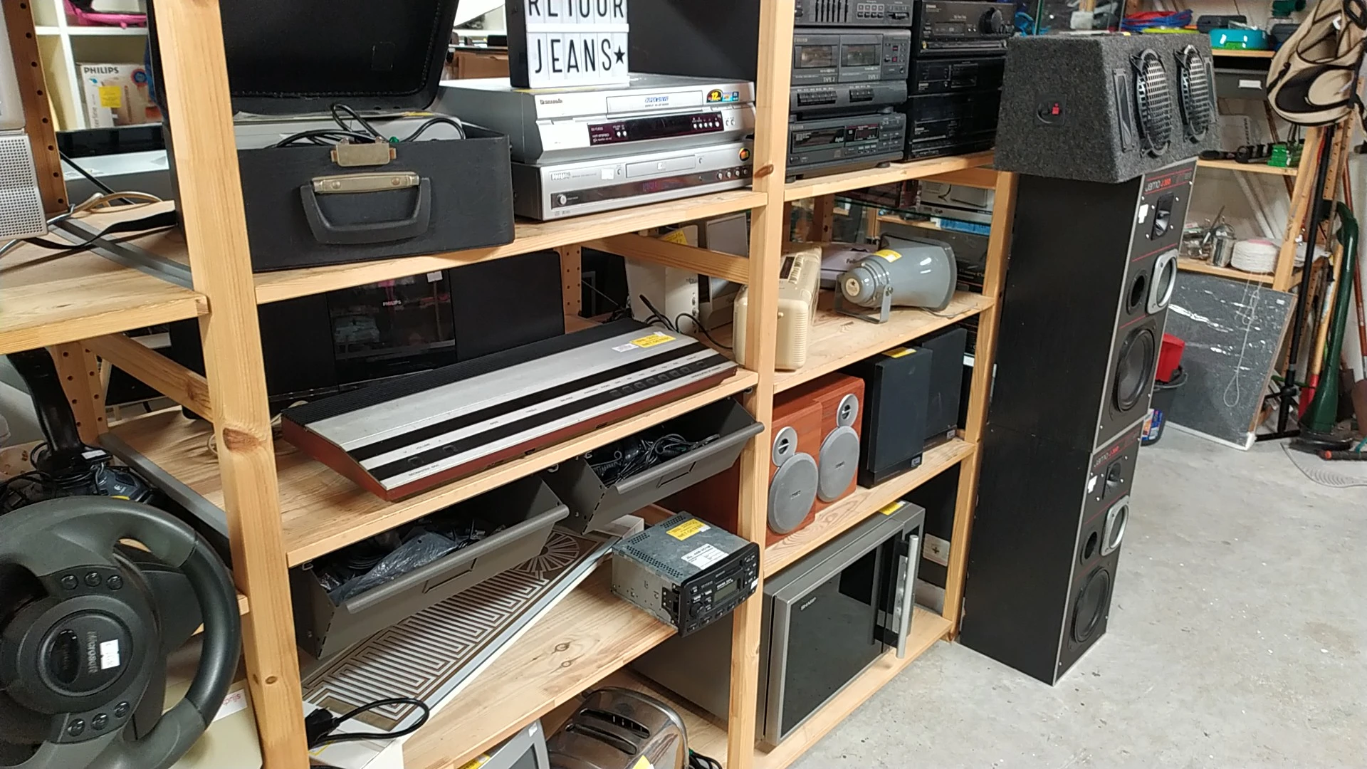 Houten stellingkast vol met elektronische apparatuur: televisies, versterkers, speakers, platenspelers en audioapparatuur