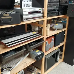 Houten stellingkast vol met elektronische apparatuur: televisies, versterkers, speakers, platenspelers en audioapparatuur