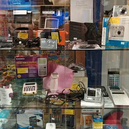 Glazen vitrinekast met elektronische apparaten: rekenmachines, digitale camera's, wasmachines en andere huishoudelijke artike