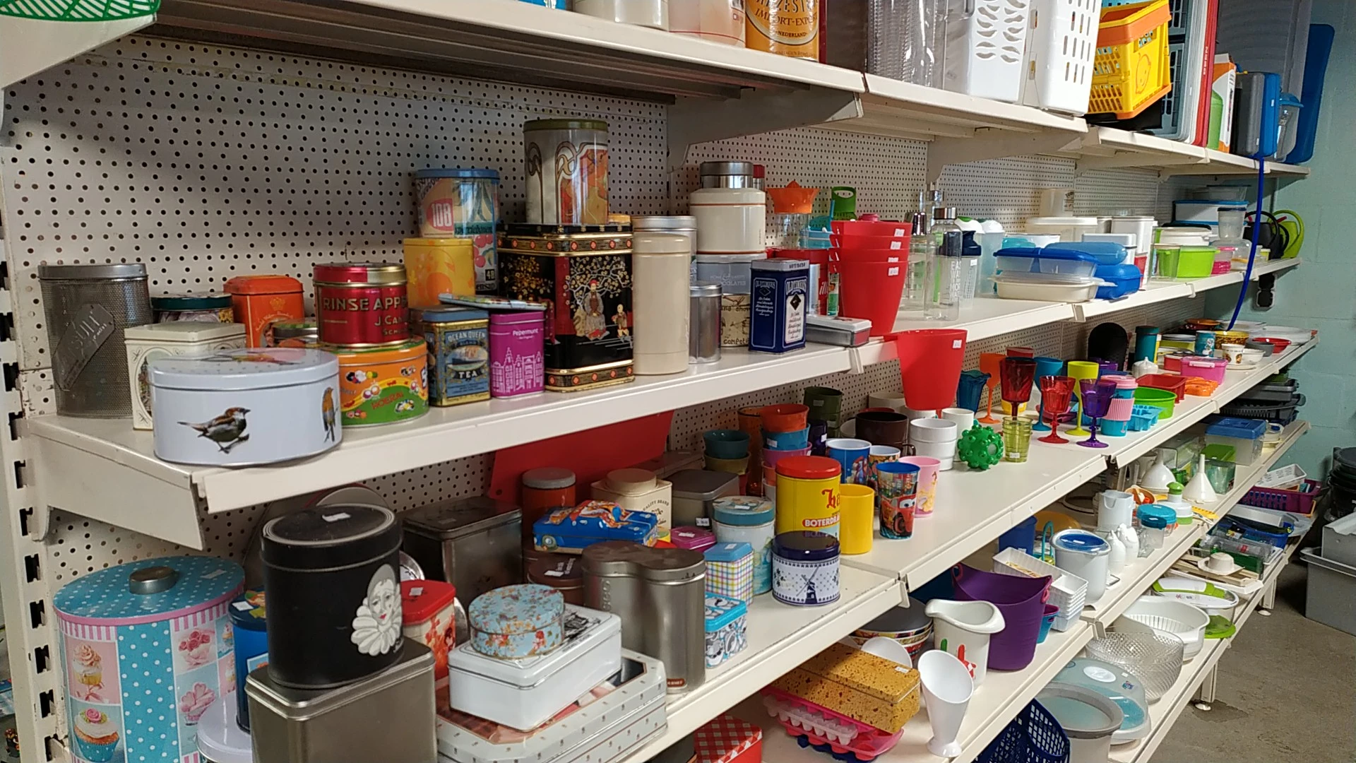 Stellingen met diverse huishoudelijke artikelen en keukenspullen in een kringloopwinkel