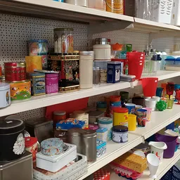 Stellingen met diverse huishoudelijke artikelen en keukenspullen in een kringloopwinkel