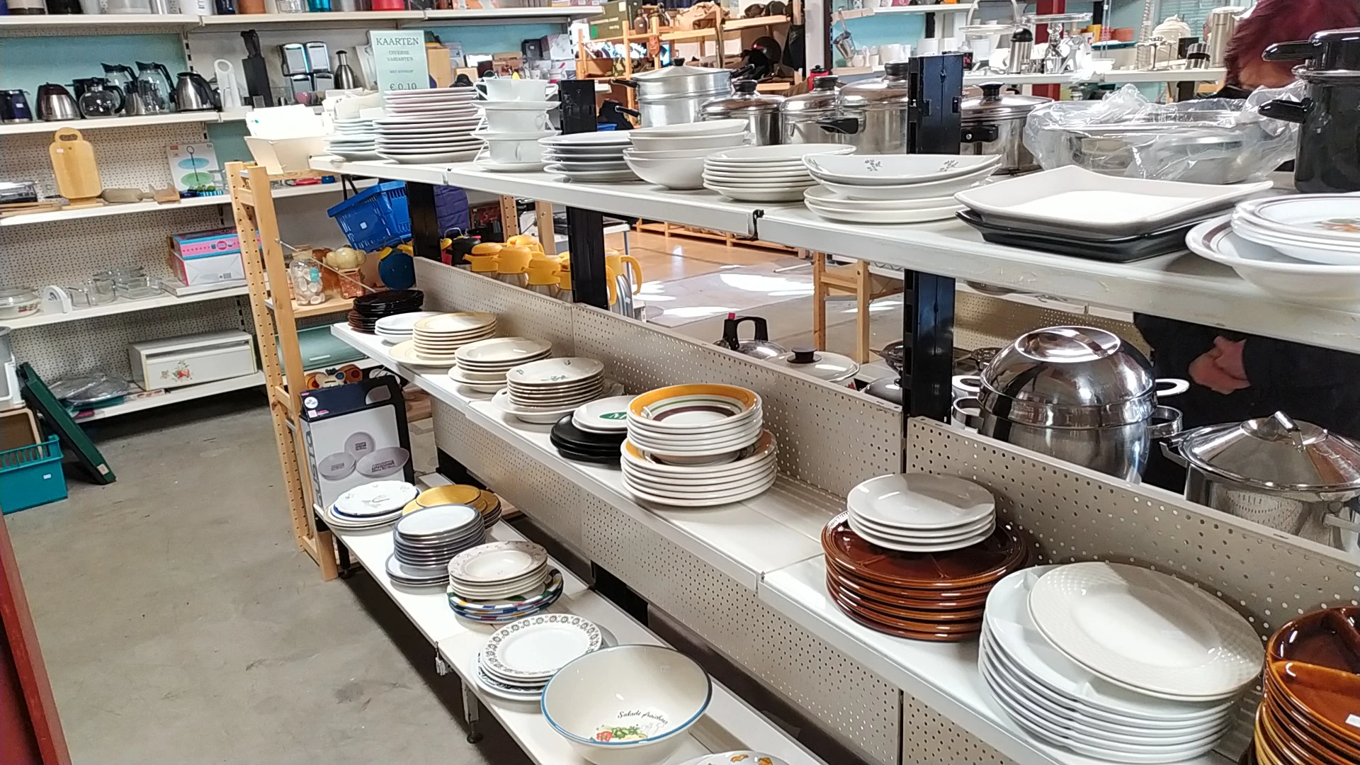 Uitgestalde servies en borden in verschillende kleuren en stijlen op stellingkasten in de winkel
