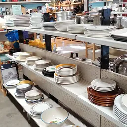 Uitgestalde servies en borden in verschillende kleuren en stijlen op stellingkasten in de winkel
